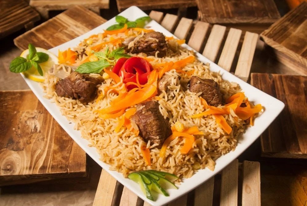 Platter of pilau rice with colorful garnish and salad accents.